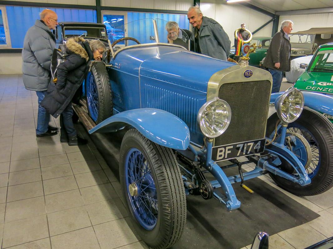 Senioren beugen sich über ein blaues Oldtimer Auto